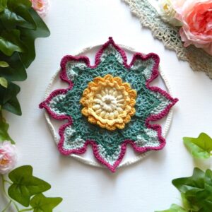Attrape-rêves fleur au crochet BLOM Attrape-rêves au crochet en forme de fleur dans des tons vert, crème, jaune et fuchsia.