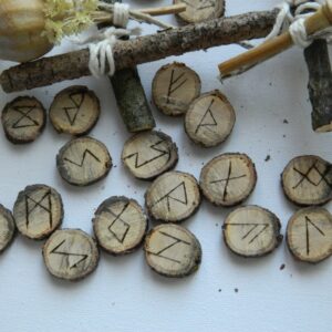 Détail des runes en chêne gravées à la main Gros plan sur plusieurs runes en chêne gravées à la main représentant les symboles du Futhark ancien.