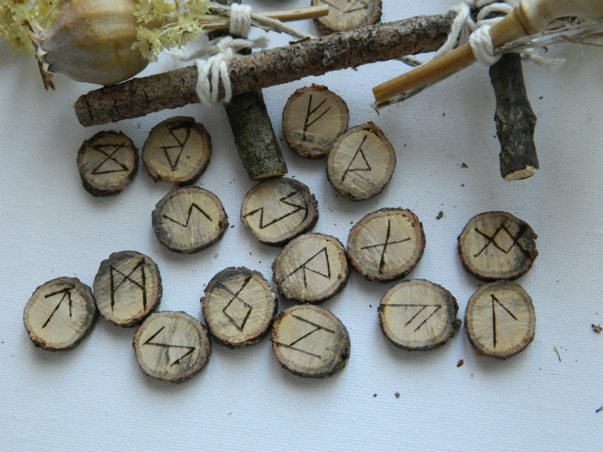 Détail des runes en chêne gravées à la main Gros plan sur plusieurs runes en chêne gravées à la main représentant les symboles du Futhark ancien.