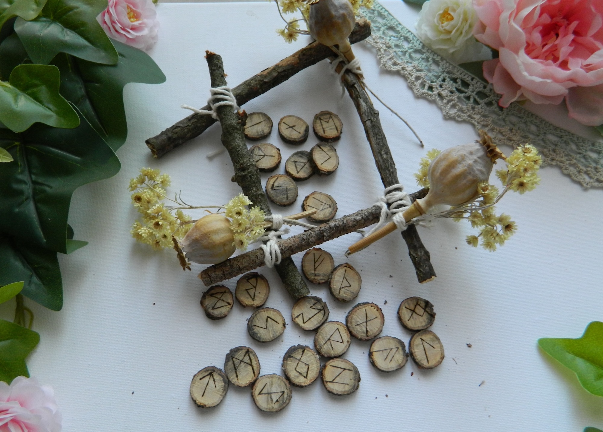Jeu de runes en chêne artisanal – Futhark ancien Jeu de 24 runes en chêne gravées à la main, inspirées du Futhark ancien, présenté dans une mise en scène naturelle avec branches, fleurs séchées et éléments végétaux.