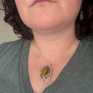 Collier BRUNN SKJOLDR en œil de tigre et au micro crochet beige porté autour du cou